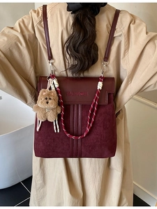 Burgundy faux leather backpack with woven handle and plush bear charm for daily commute