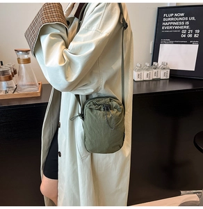 Close-up of a dark green drawstring crossbody bag in lightweight nylon fabric