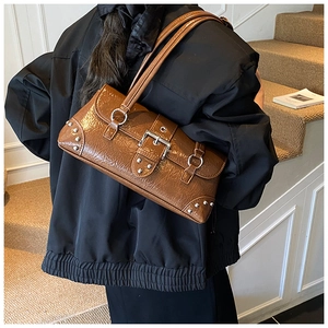 Detail view of brown vintage rivet shoulder bag with glossy crinkled leather on a model