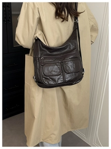 Deep brown pebble leather bag shown as a crossbody on a beige trench coat back view
