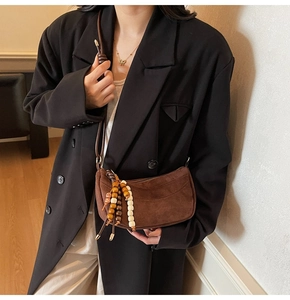 Brown suede crescent bag with vintage wooden beads on strap for a chic retro look