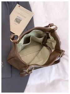 Detailed interior of the brown tote bag featuring green lining and multi-compartment storage