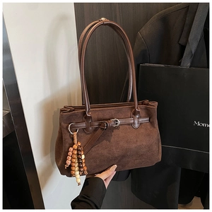 Detailed view of brown suede tote bag with stylish beaded tassels and strap buckle