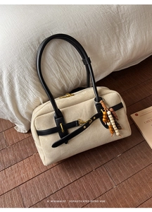 Detail of cream suede Boston bag with black leather straps and retro wooden bead charm