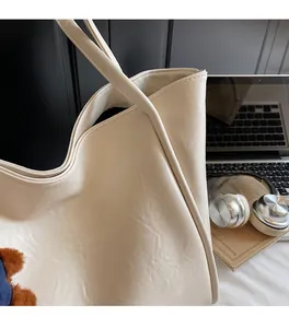 Detail of cream large tote bag with grainy texture and a cute brown plush charm