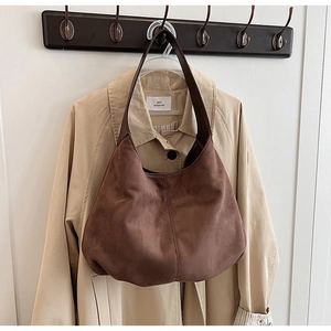 Macro detail of brown suede hobo bag with vertical stitching and leather handle