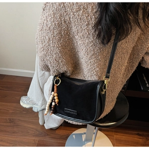 Détail de la bandoulière noire avec pompon en bois vintage et ferrures en métal doré
