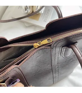 Detailed close-up of smooth gold zipper and pebble leather texture on a tote bag