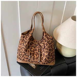 Close-up of leopard print tote bag featuring a decorative bow and brown leather handles