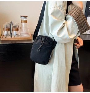 Detail of minimalist black nylon phone bag showing drawstring and fashion label