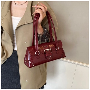 Close-up of deep red vintage rivet pillow bag with silver buckles and wrinkled leather