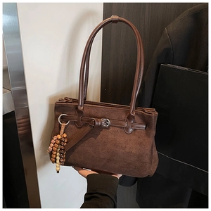Close-up of brown suede tote bag featuring unique wooden bead charms and matte texture