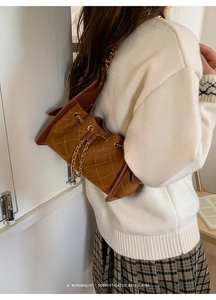 Detail of brown quilted suede bucket bag featuring golden chain and retro stitching
