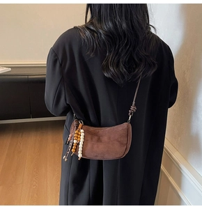 Detail of brown suede crescent bag with bohemian wooden beads and long shoulder strap