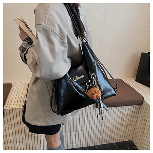 Détail du sac cabas en similicuir noir avec logo doré et breloque ours sur le modèle