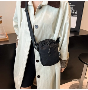 Close-up of black nylon drawstring crossbody bag with fashion tag and woven strap