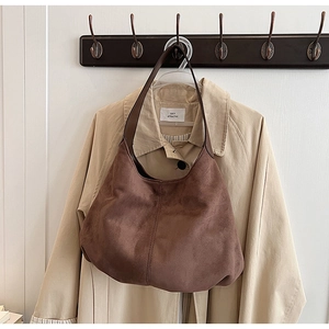 Detail view of a vintage dark coffee tote bag hanging with a beige trench coat