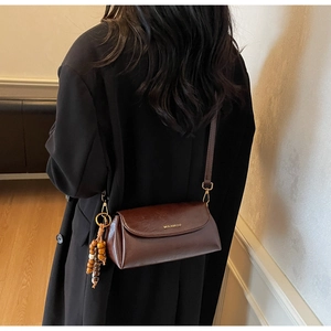 Detail of vintage brown crossbody bag with wooden bead tassel and wide shoulder strap