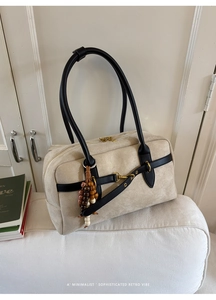 Detail of beige suede Boston bag featuring black leather straps and wooden beaded charm