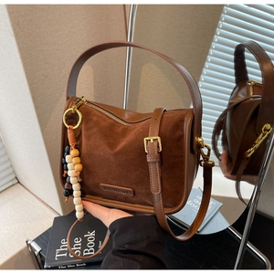 Détail d'un sac bandoulière marron rétro avec texture mate et perles décoratives en bois