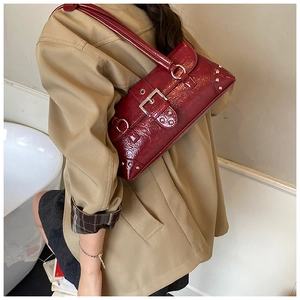 Detail view of burgundy shiny shoulder bag with silver studs and Y2K punk style hardware
