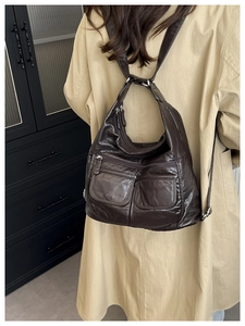 Detail view of dark brown leather backpack on model wearing a beige trench coat