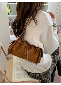 Détail d'un sac bandoulière vintage en daim matelassé marron avec chaîne dorée sur modèle