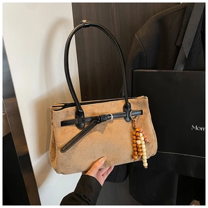 Detail of khaki suede tote bag with black leather straps and decorative wooden beads