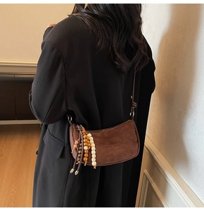Detail of dark brown matte crossbody bag with wooden bead tassels and smooth suede texture