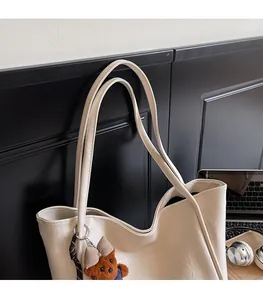 Detail of off-white large tote bag in PU leather featuring a cute brown plush bear charm