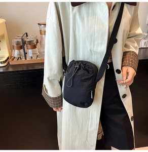 Detail view of black nylon mini crossbody phone bag with drawstring closure and fashion label