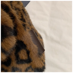 Dettaglio macro della trama in pelliccia sintetica leopardata con bordo in pelle marrone
