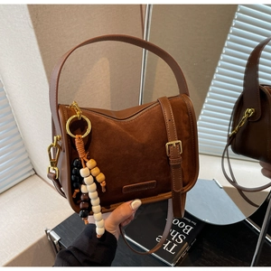 Détail du sac à bandoulière vintage marron en daim avec porte-clés à perles