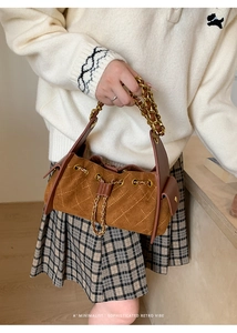 Détail d'un sac matelassé marron avec chaîne dorée et fermeture par cordon de serrage