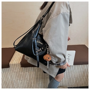 Détail du sac hobo en cuir PU noir avec logo métallique et breloque ours sur la bandoulière