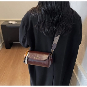 Detail of vintage dark brown crossbody bag with ethnic patterned strap and beaded tassel