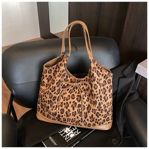 Detail of leopard print tote bag featuring brown leather trim and small bow decoration