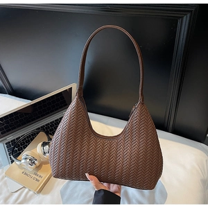 Macro della trama intrecciata marrone e della chiusura a zip della borsa hobo