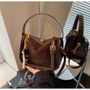 Détail du sac bandoulière en daim marron avec perles en bois et ferrures dorées
