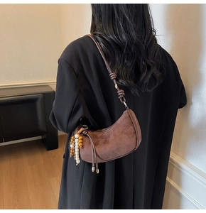 Detail of brown suede crescent bag with wooden beads and knotted shoulder strap