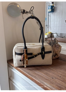 Detail of retro cream suede Boston bag with black leather straps and wooden bead charm