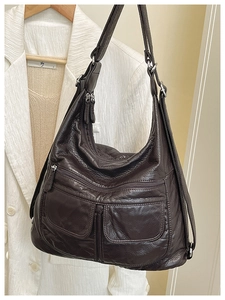 Detail of dark brown pebble leather texture and multi-pocket structure of a utility bag