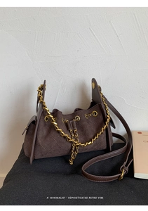 Detailed macro of dark brown suede crossbody bag with elegant diamond quilting and chain