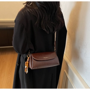 Detail view of vintage brown leather bag with geometric strap and wooden bead charm
