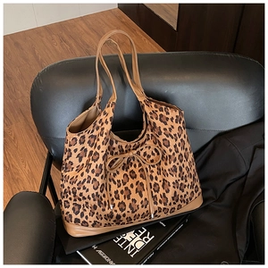 Detail of leopard print tote bag with bow tie accent on a stylish leather sofa