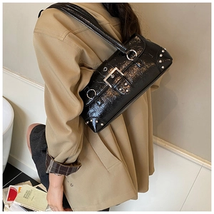 Detail of black vintage shoulder bag with silver rivets and buckle on a trench coat