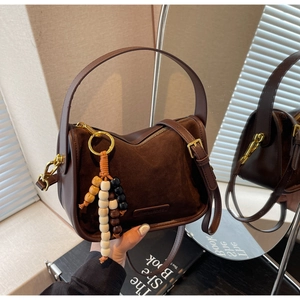 Détail du sac besace marron foncé en daim mat avec pompon en perles de bois