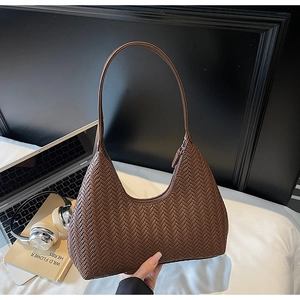 Dettaglio di una borsa hobo marrone intrecciata con motivo a spina di pesce per donna