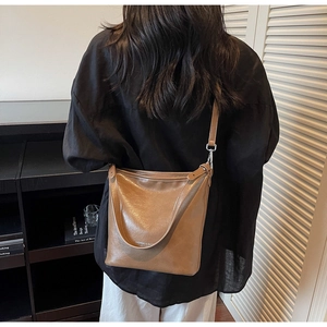 Sac seau rétro marron en cuir PU avec motif litchi porté à l'épaule par le mannequin
