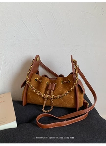 Detail of brown quilted suede bucket bag featuring golden chain and drawstring closure